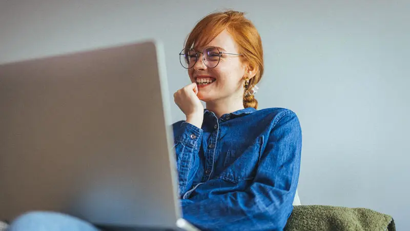 Photograph of a smiling person looking at their laptop