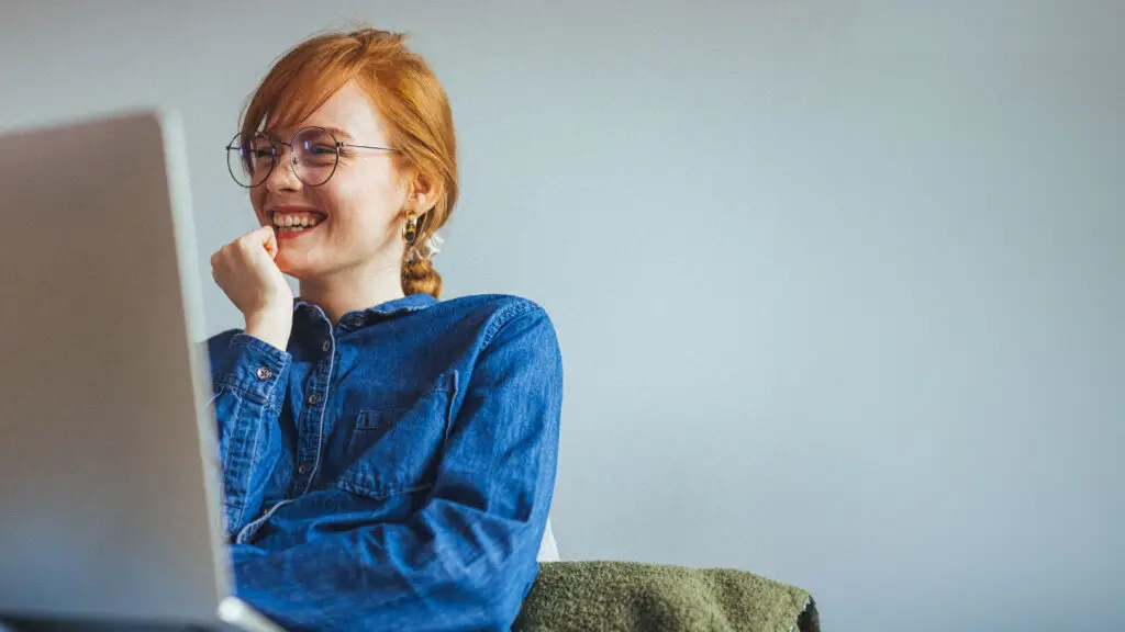 Photograph of a smiling person looking at their laptop