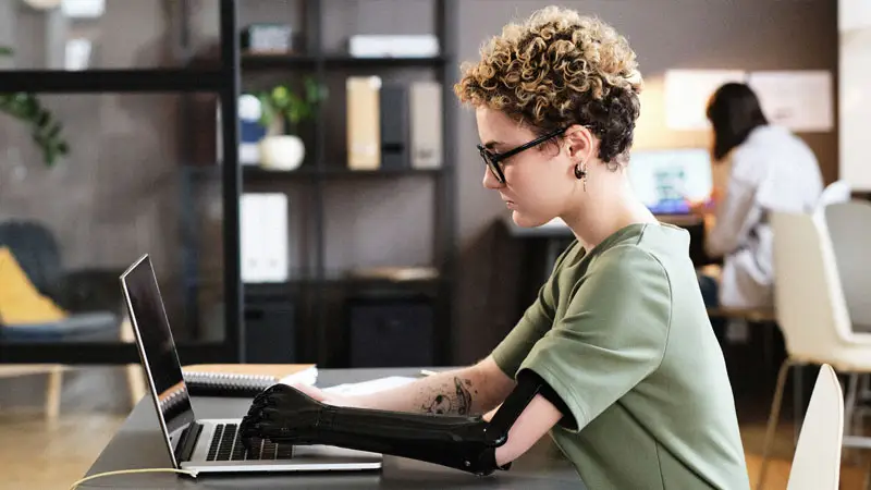 Photograph of a person using a laptop while sitting at a desk