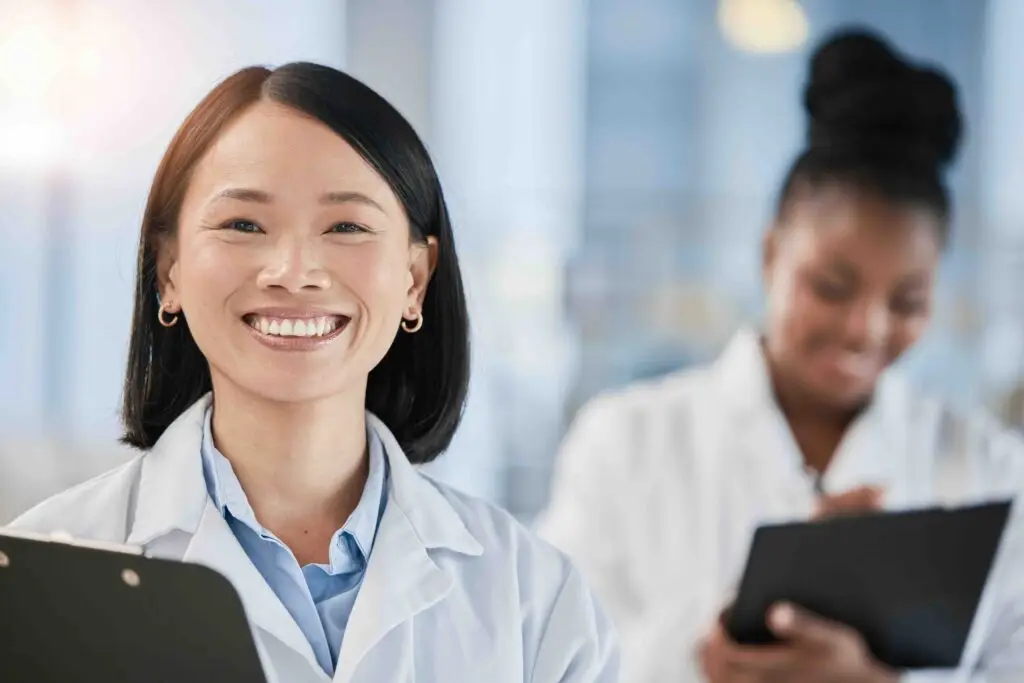 Asian doctor woman, checklist and portrait with smile, planning or happy at clinic with african exp.