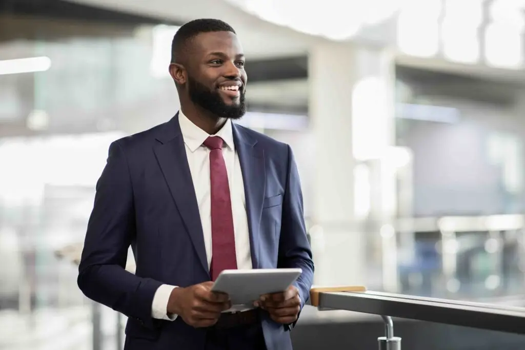 Cheerful black manager with digital tablet walking by office