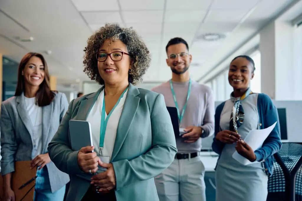 Mature CEO and her business team in the office looking at camera.