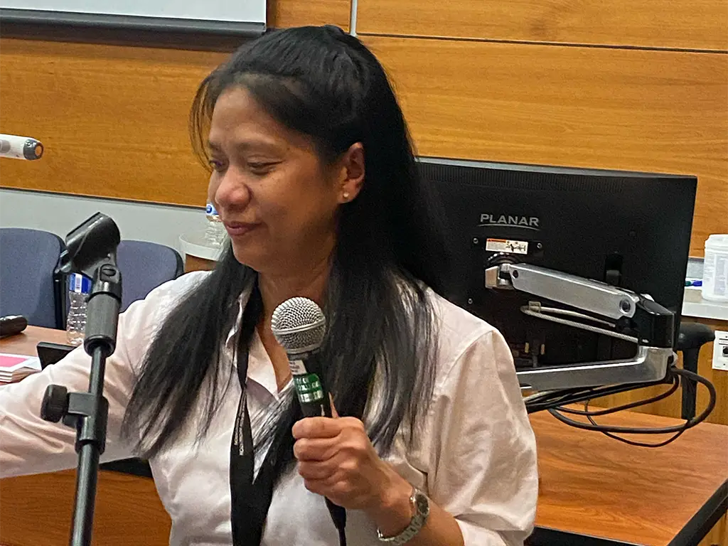 Angela Tecson looking down at the podium with a mic in hand.