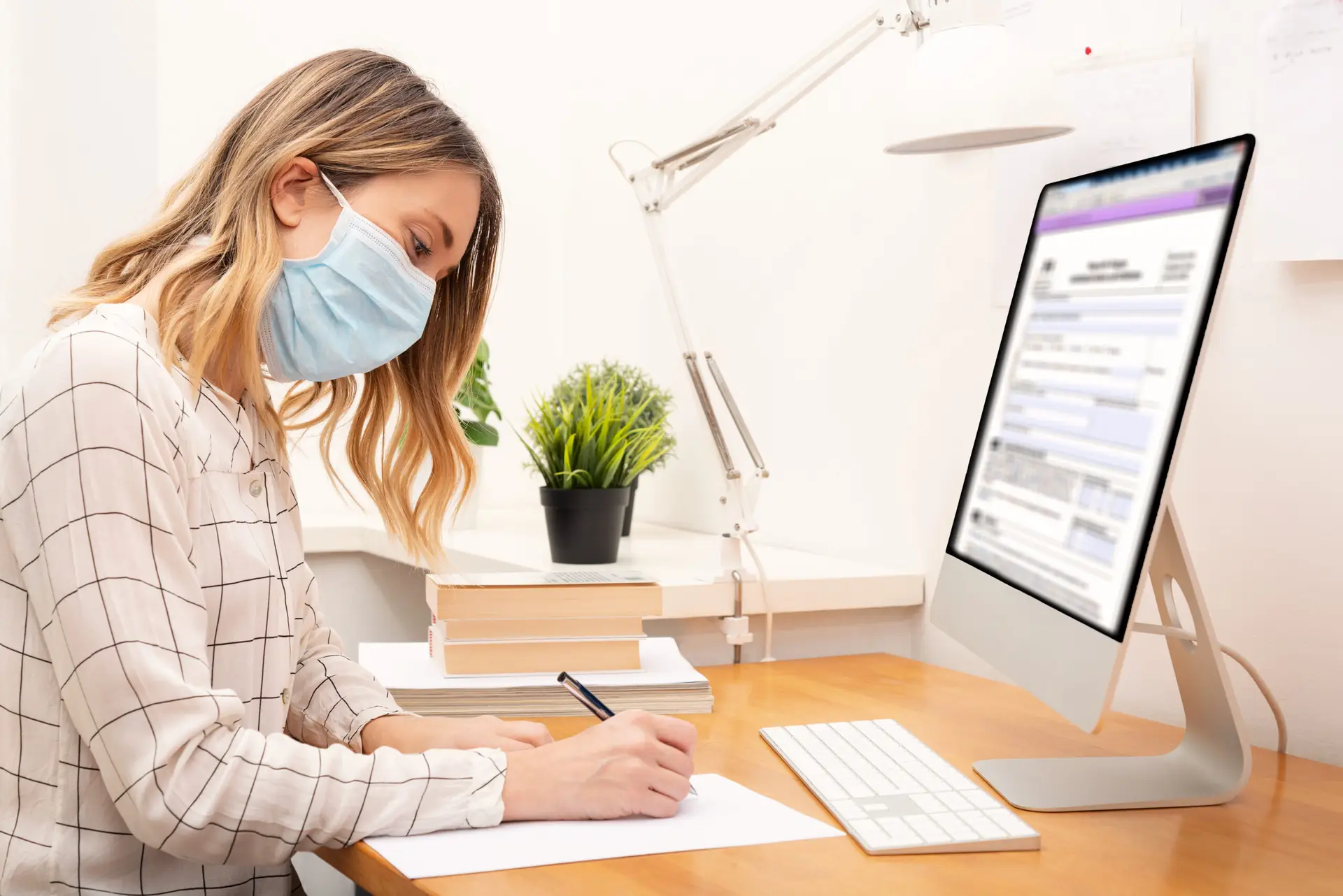 Woman with a mask works at a home office setup